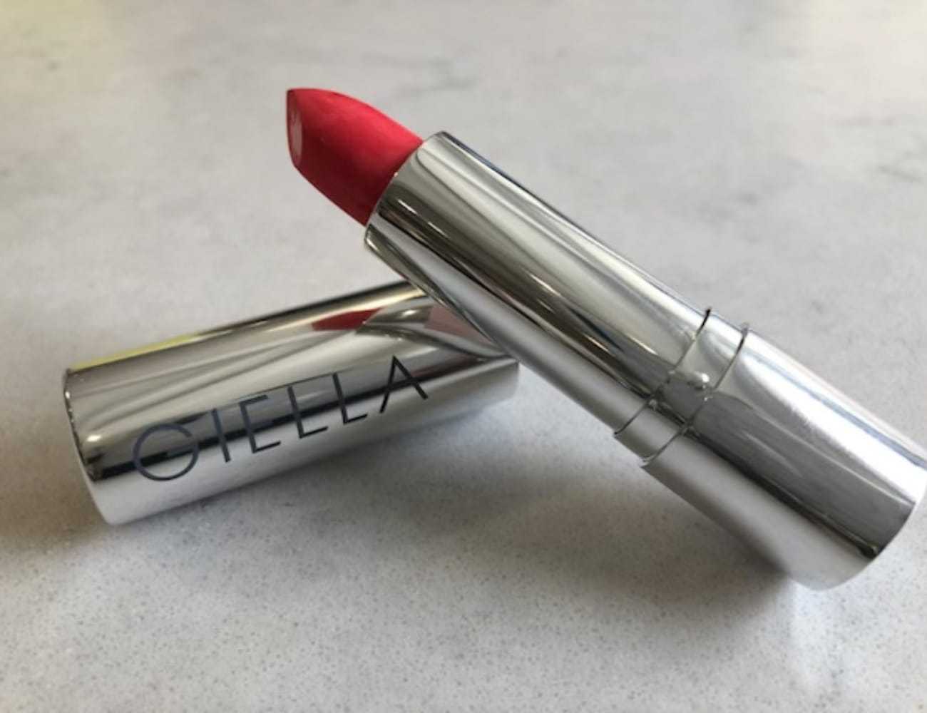 Red lipstick in silver tube on a countertop, branded with "Giella.