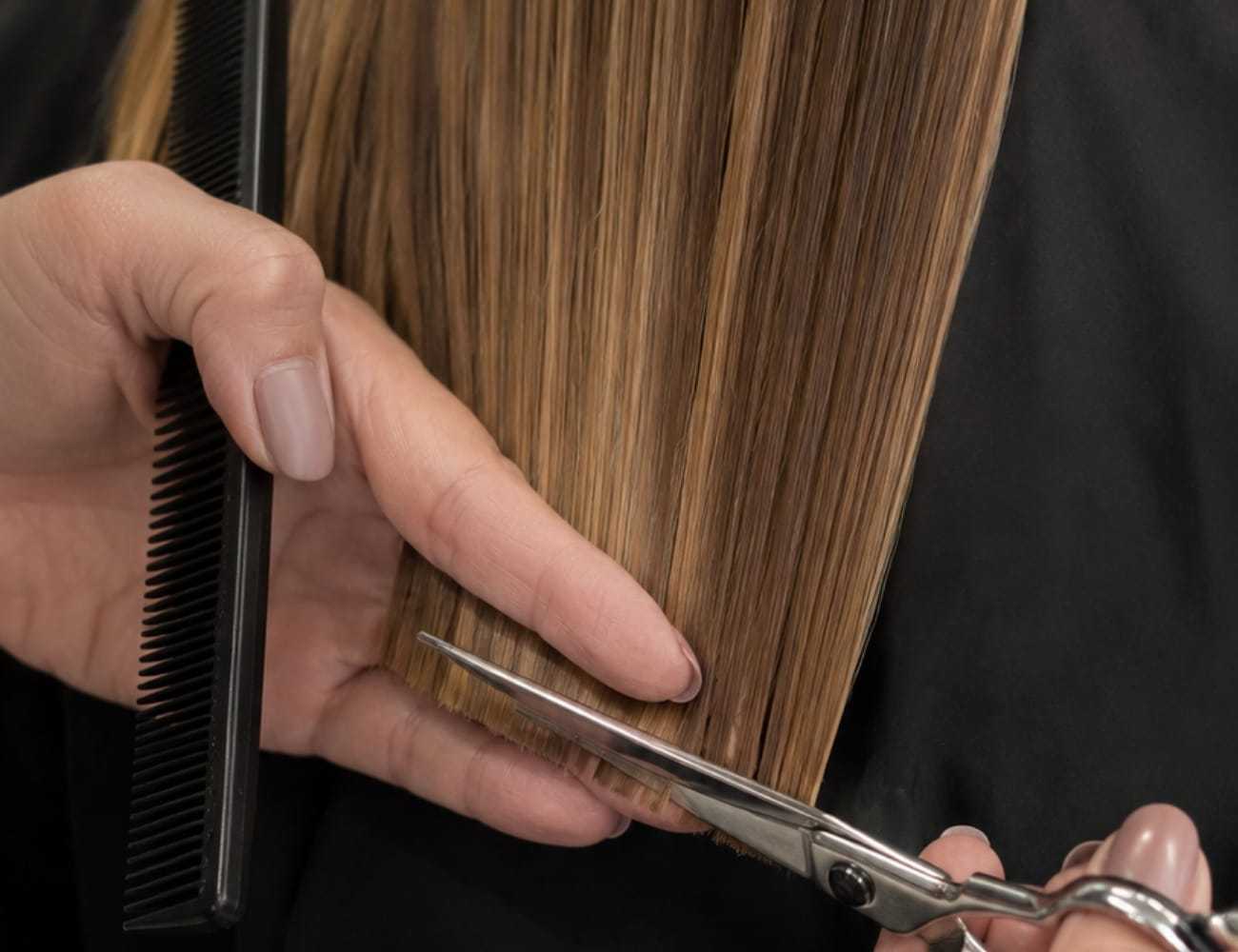 Hair being trimmed with scissors and comb in a salon setting.