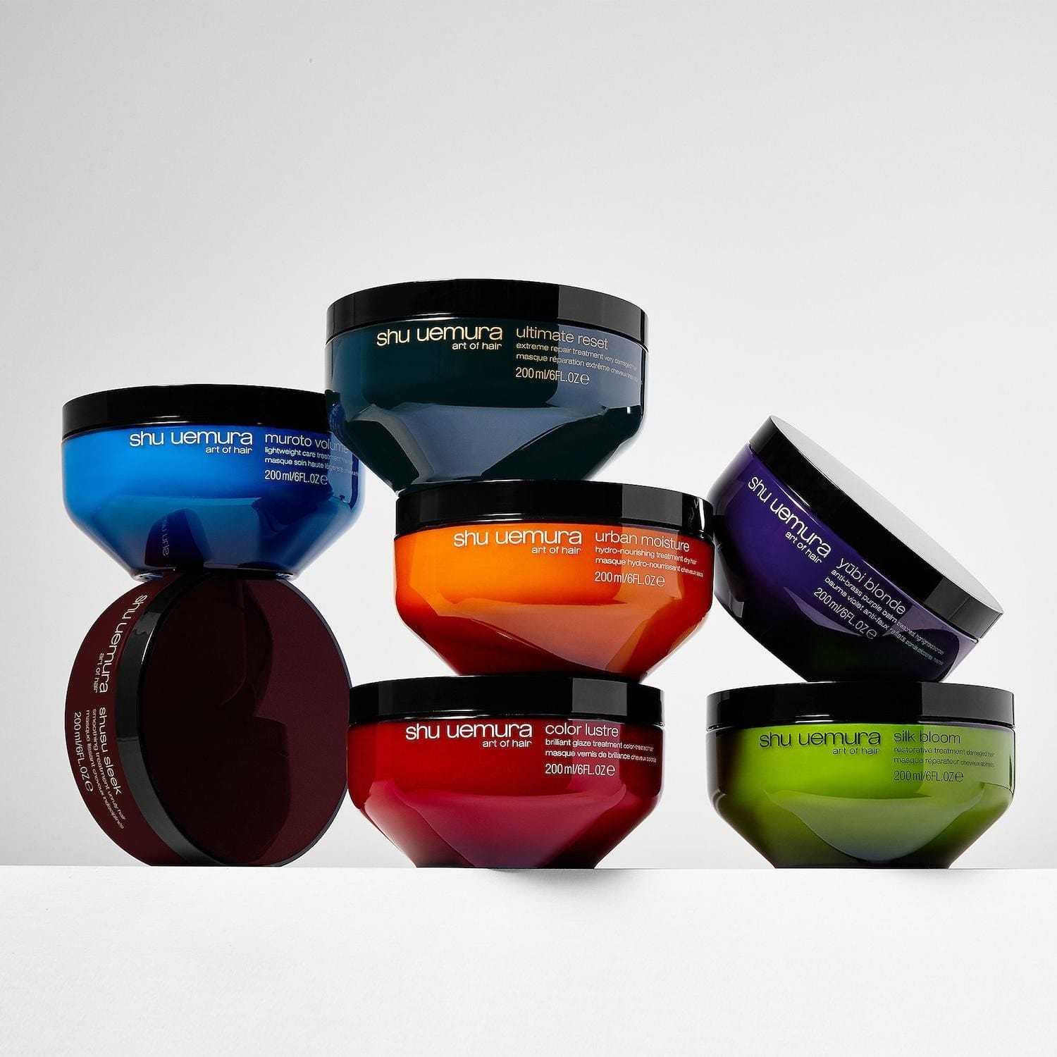 Colorful Shu Uemura hair product containers arranged artfully on a white surface.