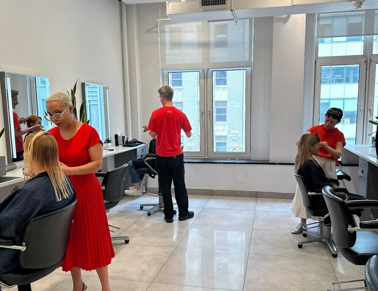 Salon staff styling clients' hair in a bright, modern setting.