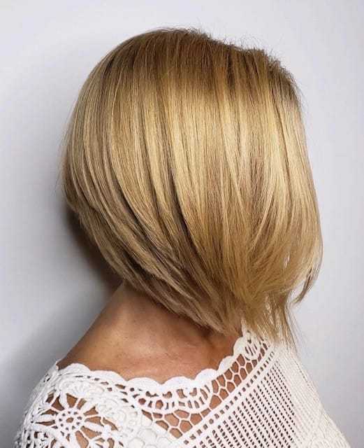 Short blonde bob haircut on a person with a white lace top.
